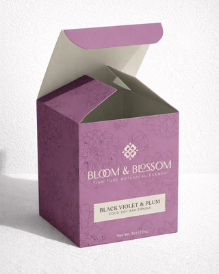 Custom printed folding carton packaging for Bloom & Blossom Black Violet & Plum coco soy candle, shown with peeling product label detail on luxury candle box premium CPG packaging design.